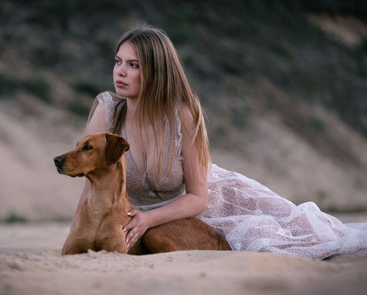 Hund mit Besitzer liegend im Sand im Kleid